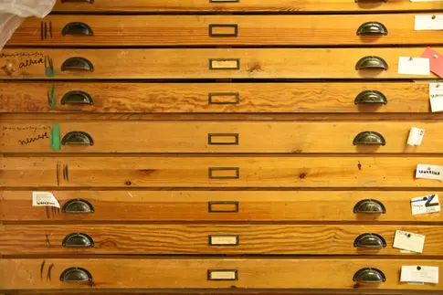 Frontalansicht der Schubladen eines alten Grafikschranks aus Holz mit vielen Gebrauchsspuren